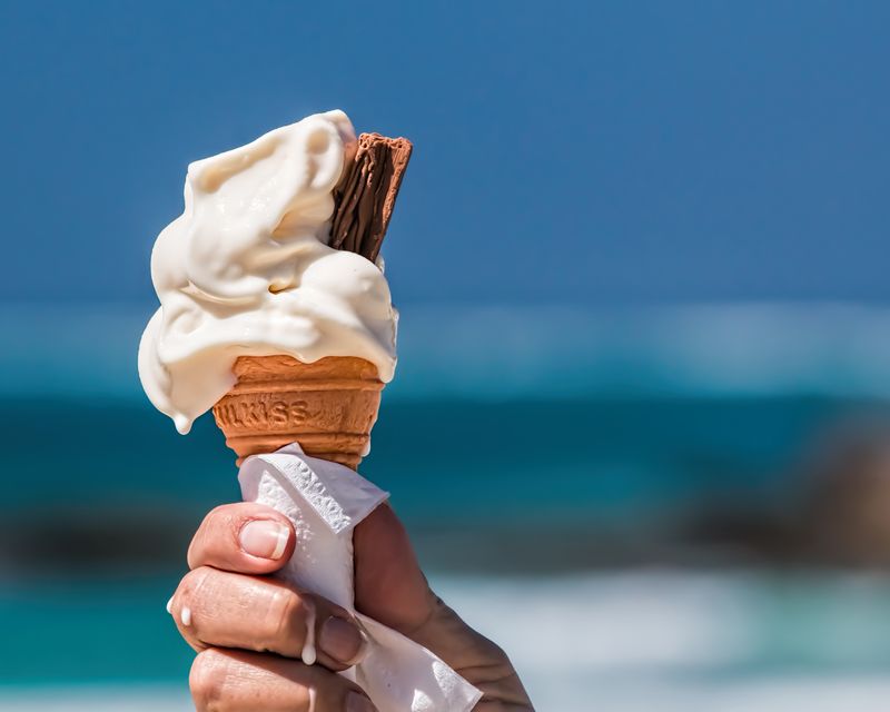 A vanilla soft-serve ice cream cone at the beach. Temporary concept photography.