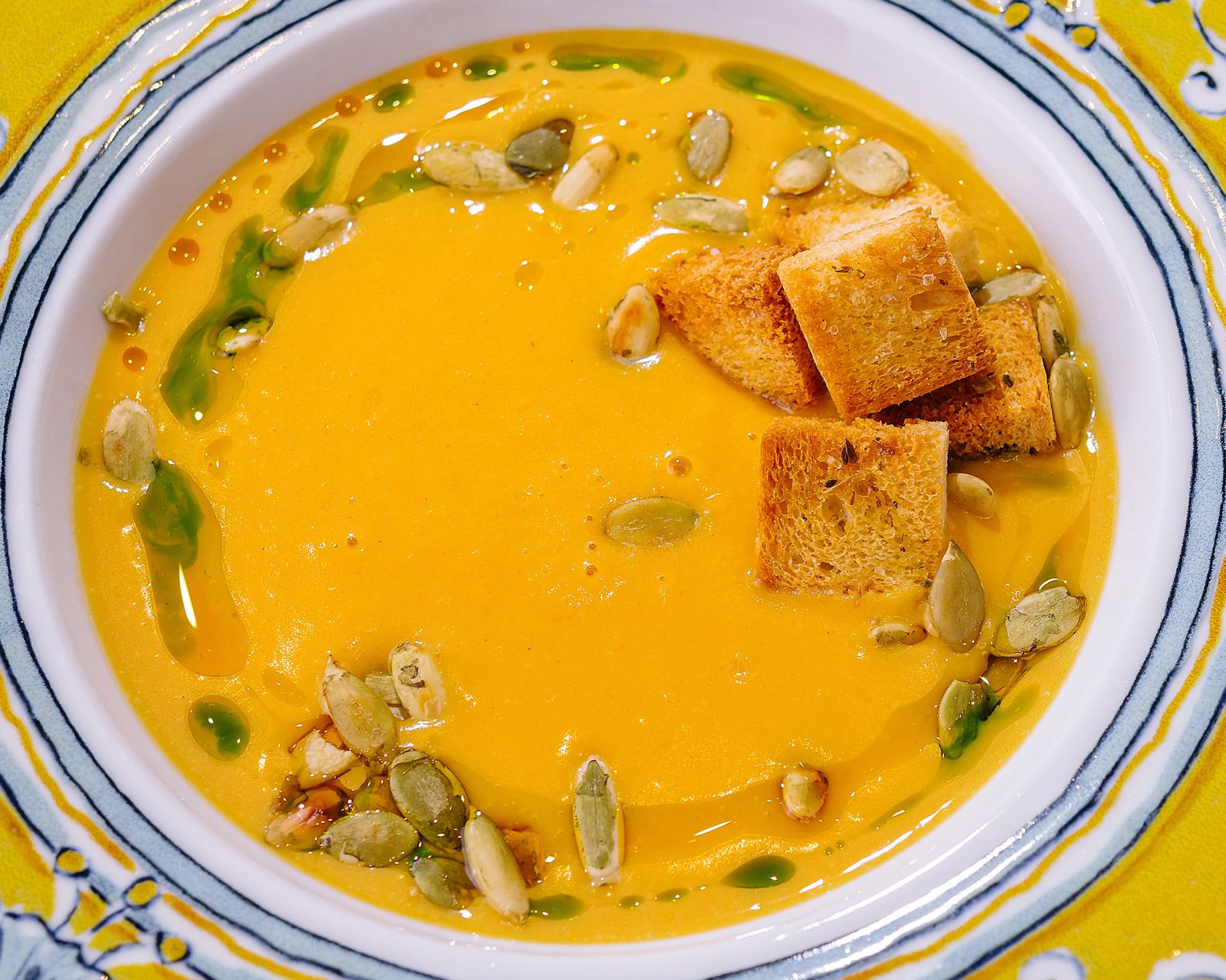 A creamy soup topped with seeds and croutons. Temporary concept photography.