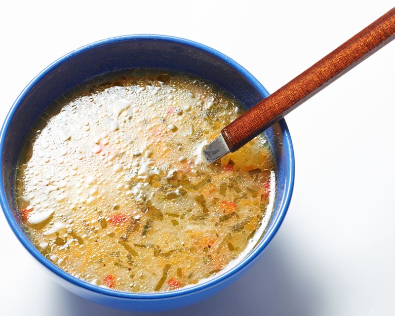 A clear broth soup in a blue bowl. Temporary concept photography.