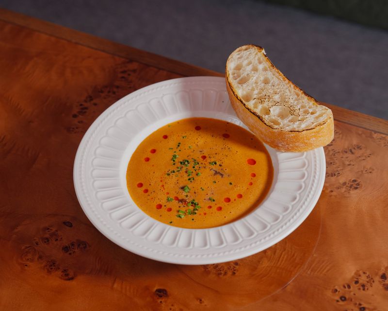 A plated cream soup with a slice of bread. Temporary concept photography.