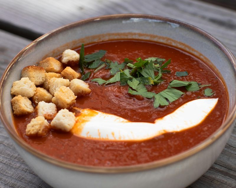 A bowl of tomato soup with croutons. Temporary concept photography.