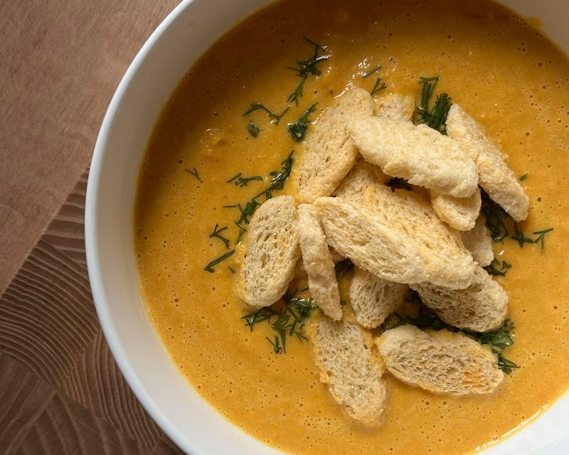 A yellow soup topped with sliced bread. Temporary concept photography.