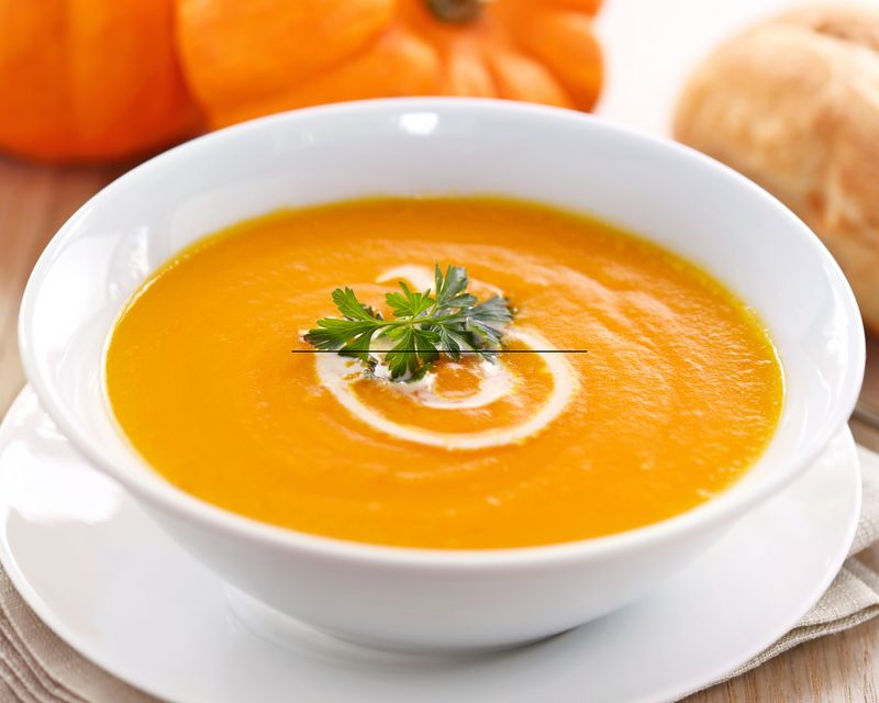 A smooth orange soup in a white bowl. Supporting winter atmosphere photography, not a listed menu item.