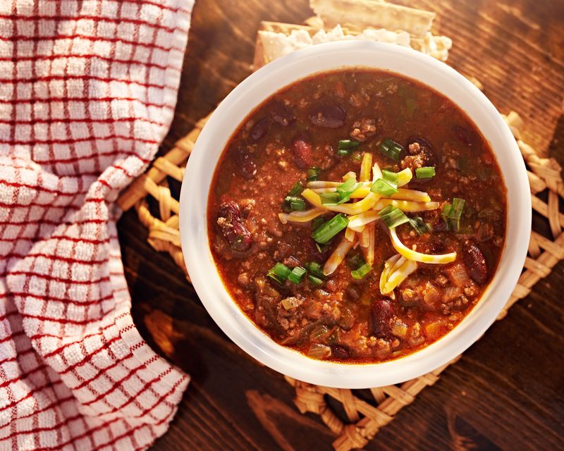 Chili in a white bowl on a woven mat. Temporary concept photography.