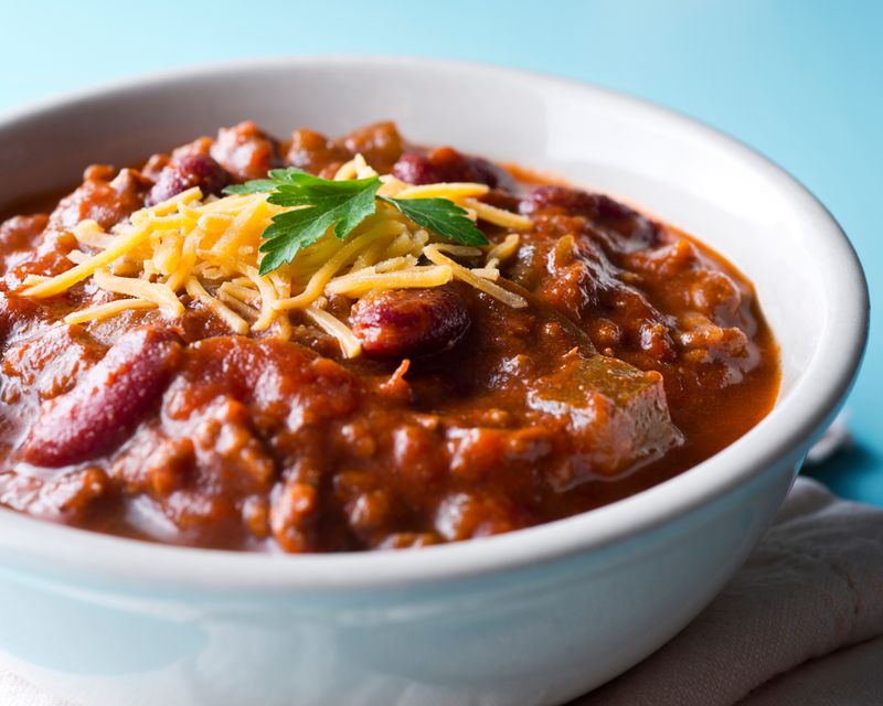 A close-up bowl of chili topped with cheese. Temporary concept photography.